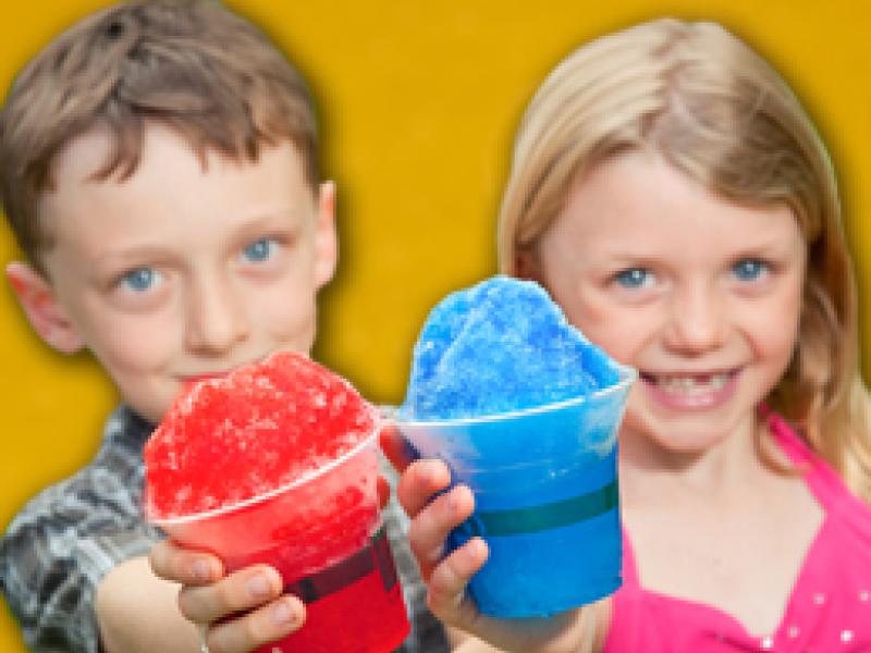 Two children holding red and blue snow cone treats