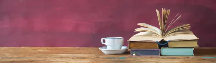 Stacked books next to a cup and saucer.