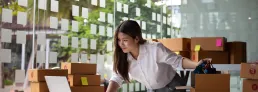photo of a young woman packing boxes for shipping