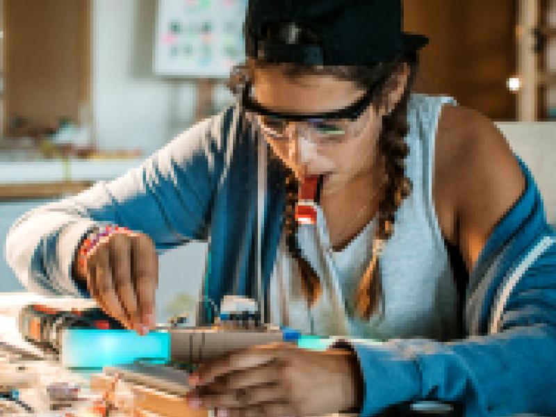 Teenage girl working on a circuit board.
