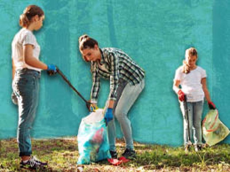 photo of three people picking up trash in a park