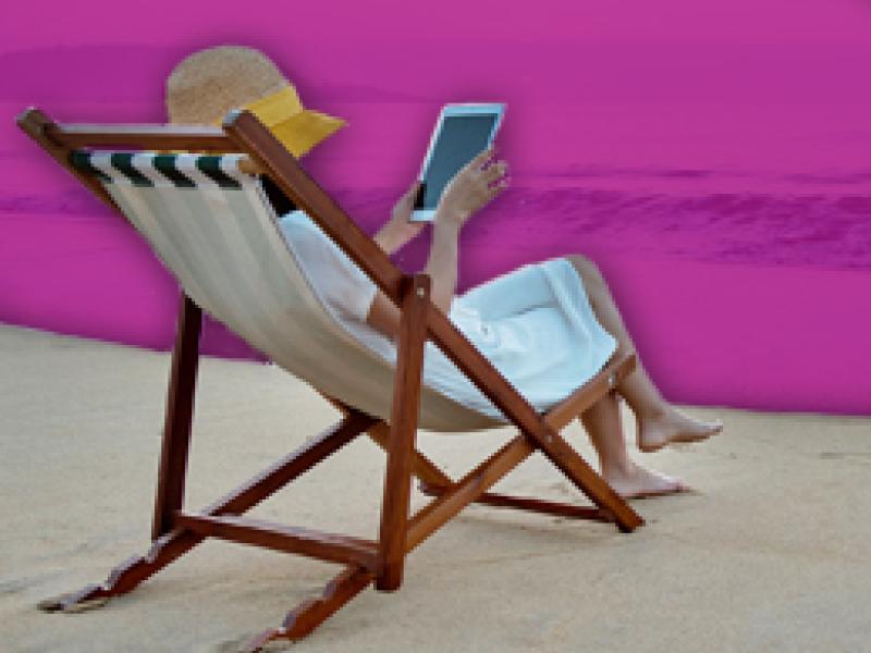 woman reading on a tablet at the beack