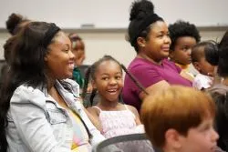 Smiling kids sitting in a crowd